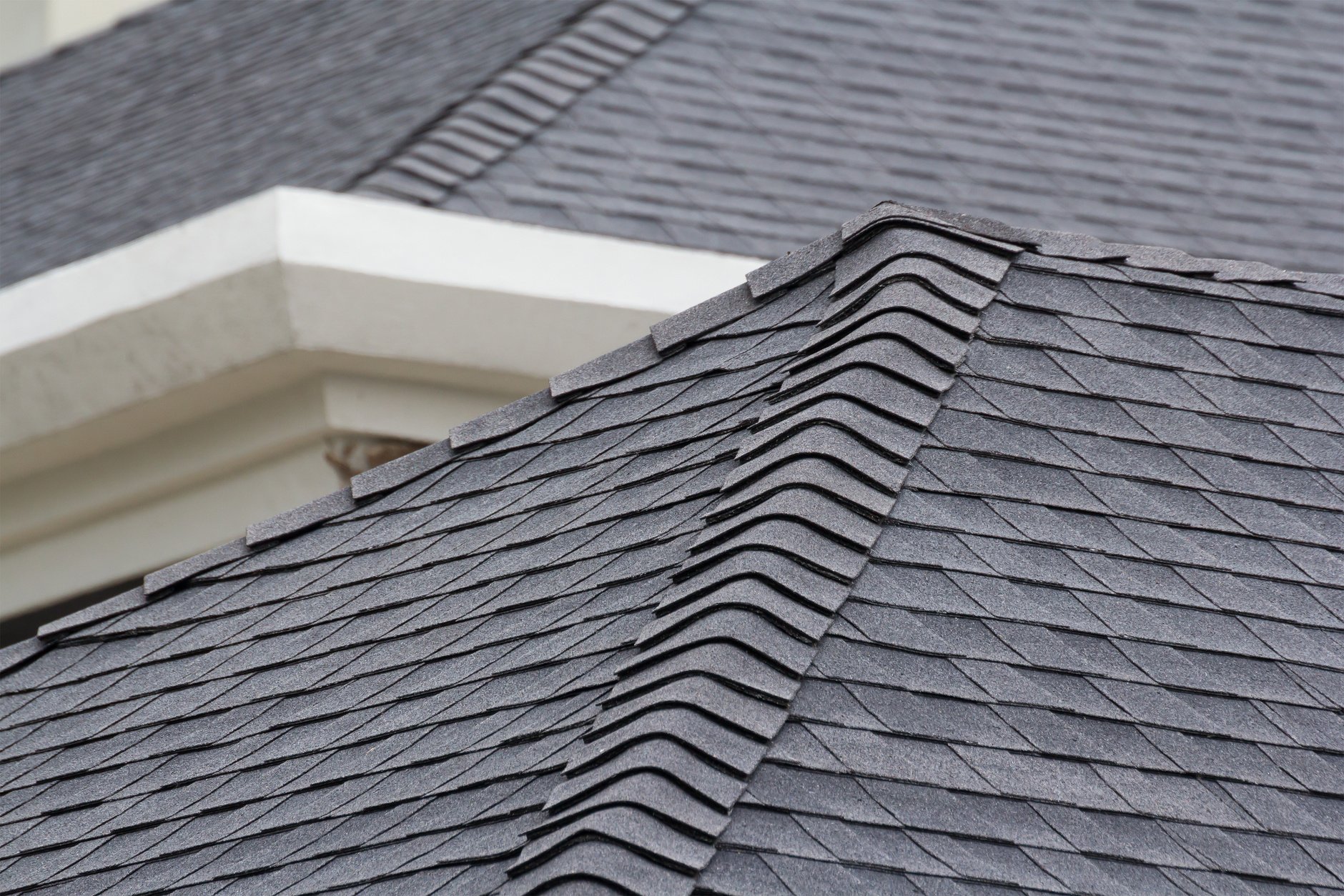 edge of Roof shingles on top of the house, dark asphalt tiles on the roof background.